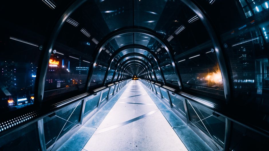 Oświetlony szklany tunel spacerowy w miejskiej scenerii nocą