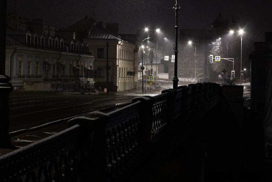 Ciemna miejska ulica w deszczu, oświetlona ulicznymi lampami
